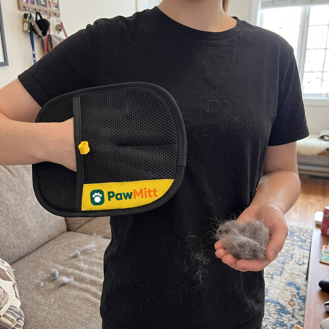 PawMitt glove worn on a hand, with the fur it lifted off a sofa cushion